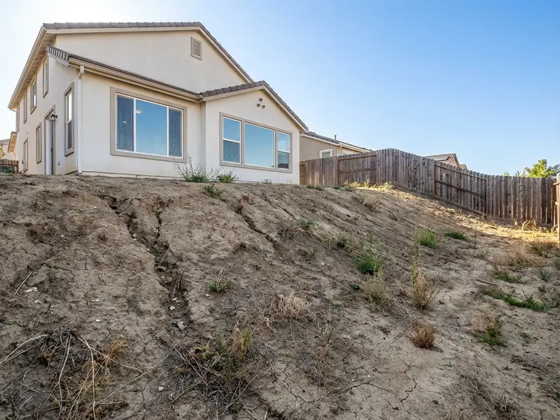 Backyard before retaining wall installation — uneven slope
